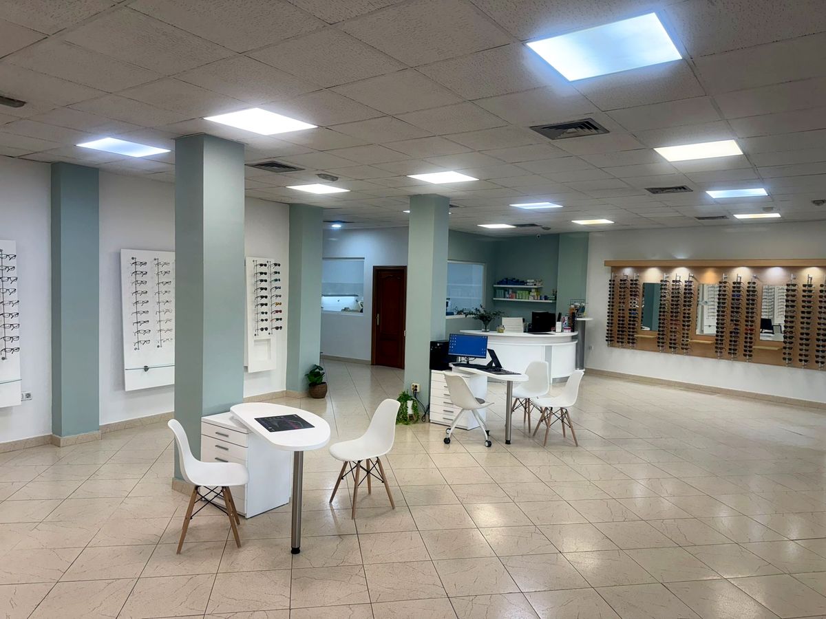Interior de la óptica Gaféate, con columnas verde menta, mesas de atención y expositores de monturas